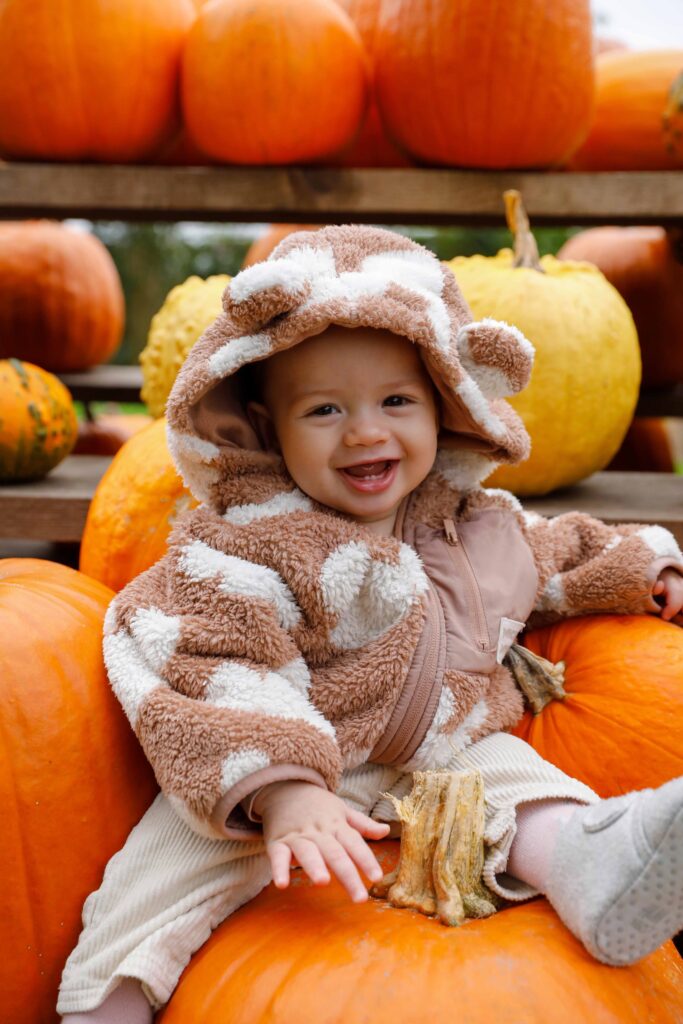 Lachendes Baby zwischen Kürbissen bei einem Herbst-Fotoshooting