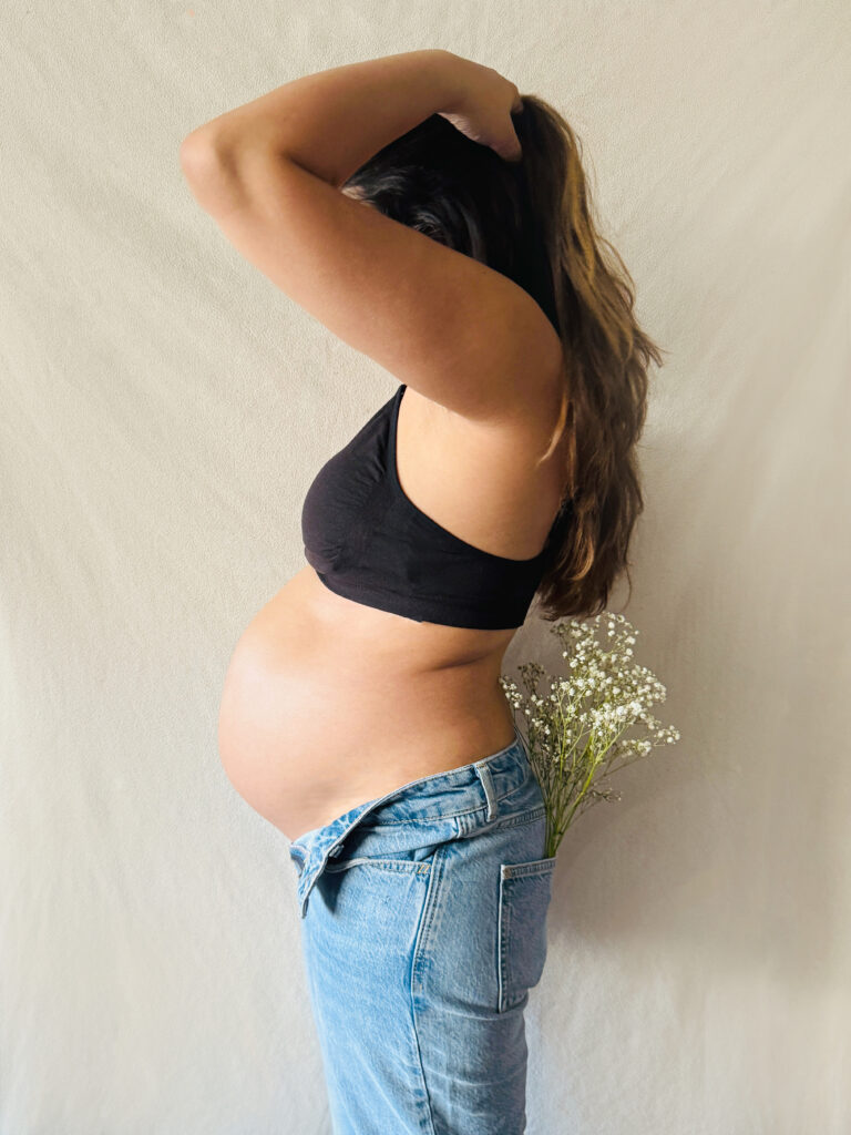 Pregnant woman with a baby bump holding a bouquet of white flowers