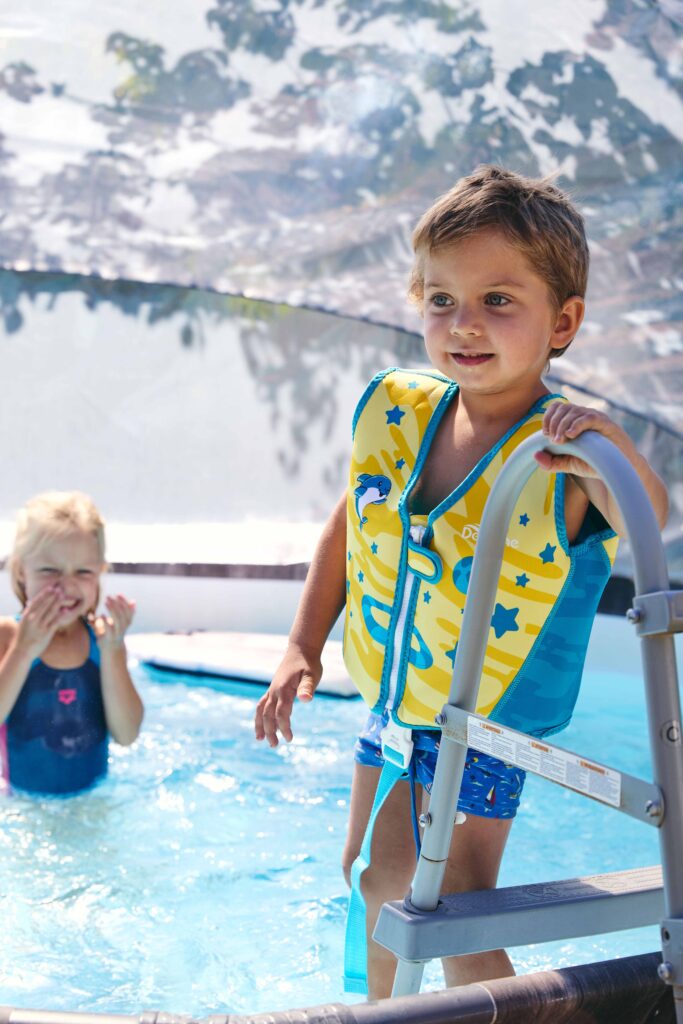 Kind in Schwimmweste steht am Pool