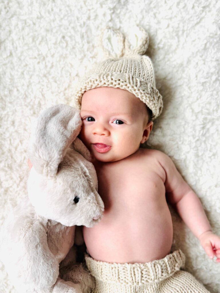 Four-month-old baby with a soft toy bunny on a blanket