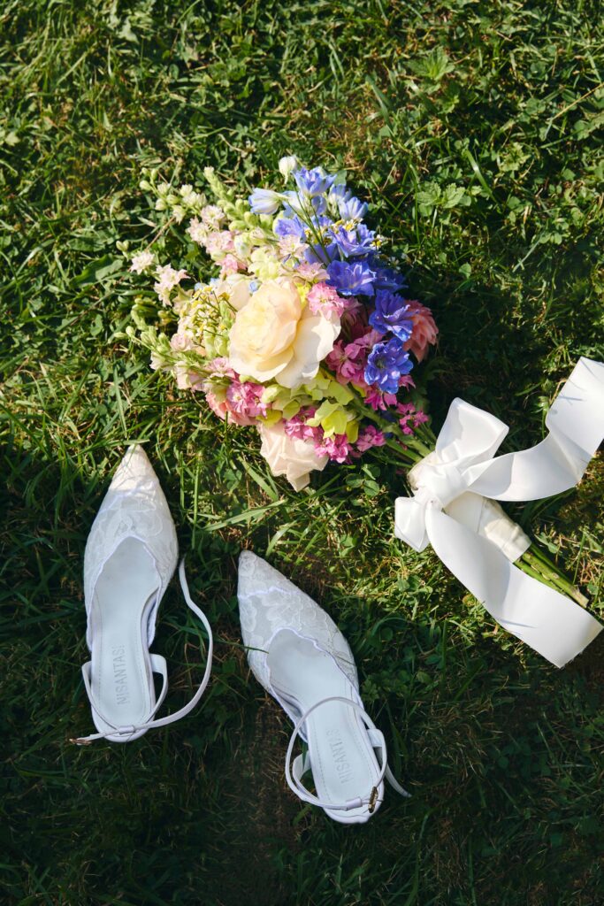 Bunter Brautstrauß und weiße Brautschuhe auf einer Wiese